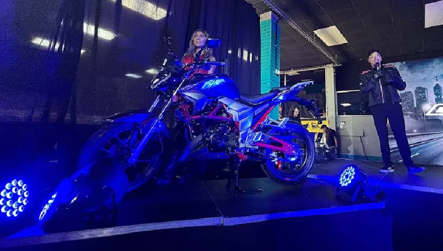 motocicleta estacionada, atrás una mujer y un hombre con micrófono