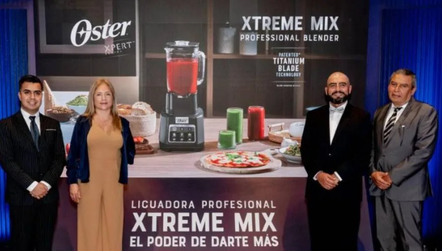 3 hombres y 1 mujer junto a un banner de la licuadora Oster Xtreme Mix