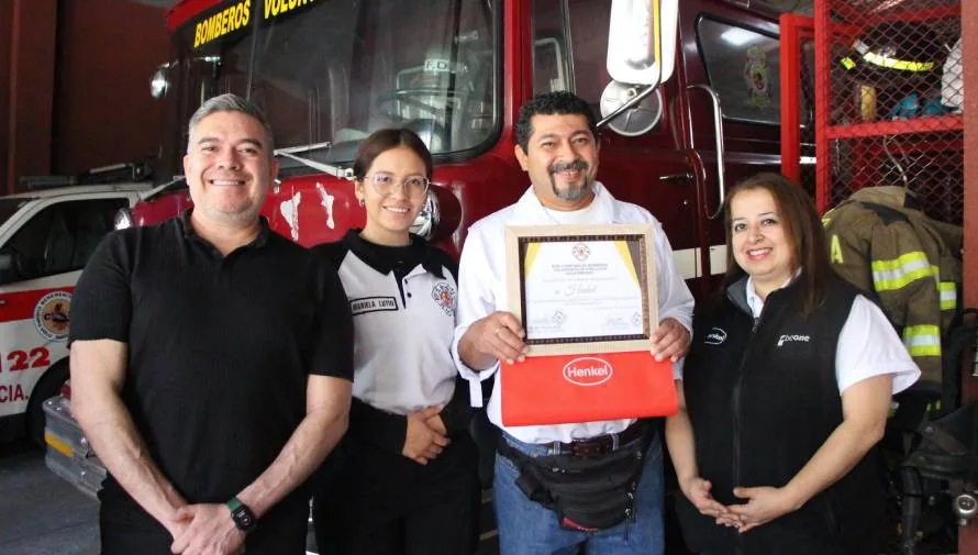 personas frente a una patrulla de bomberos sosteniendo un diploma