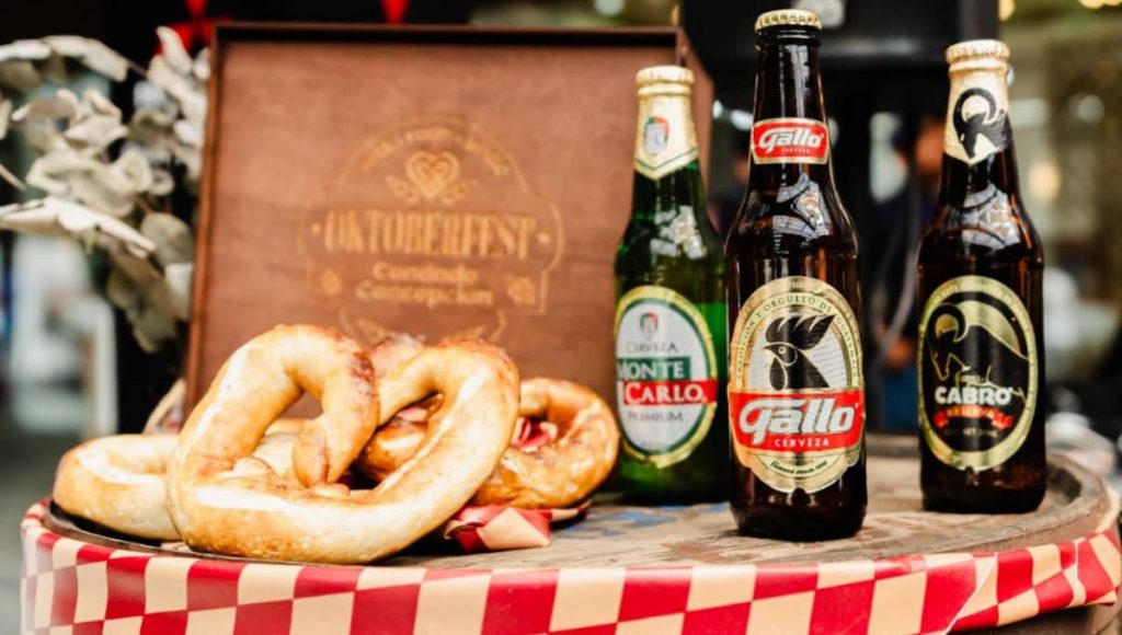 botellas de cerveza gallo, cabro, montecarlo, sobre una mesa junto a un menú del oktoberfest 2026 de condado concepción guatemala